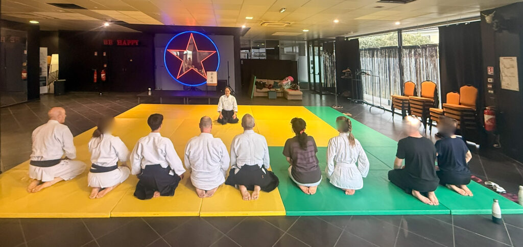 une dizaine de personnes assises pendant la séance de salut en début de cours d'aikido,